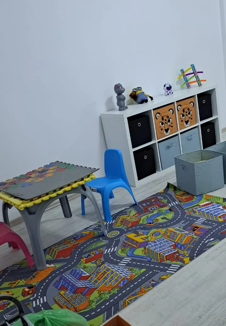 Sala noastră de terapie: covor cu drumuri, mese mici, scaune colorate și rafturi cu jocuri